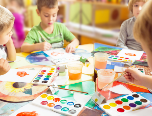 Groupe d’enfants s’amusant autour d’une table en dessinant avec des palettes de couleurs