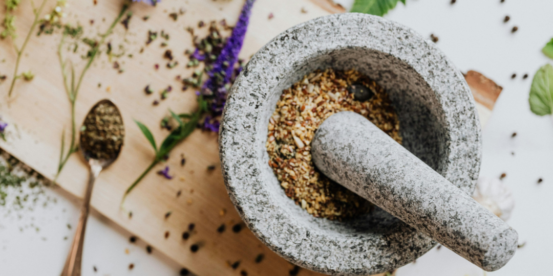 Épices et plantes dans un bol, prêtes à être écrasées pour l'alimentation