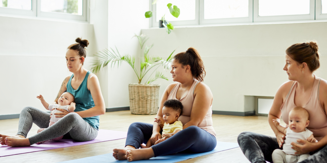 Femmes participant à une activité en groupe, assises sur le sol avec des enfants sur les genoux