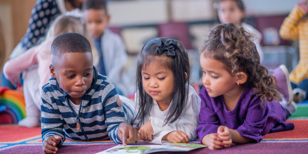 Enfants allongés sur le ventre, les yeux rivés sur un livre
