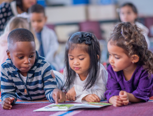 Enfants allongés sur le ventre, les yeux rivés sur un livre