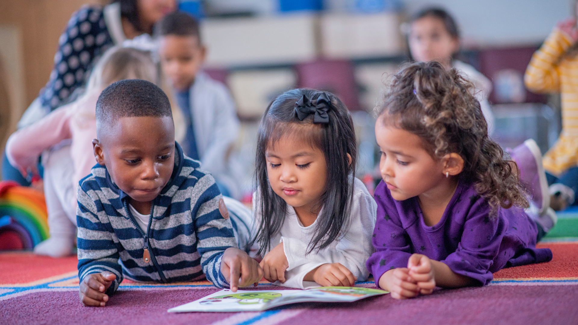 Enfants allongés sur le ventre, les yeux rivés sur un livre