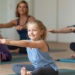 Cours de Pilates avec des enfants souriants assis, suivis de leurs parents