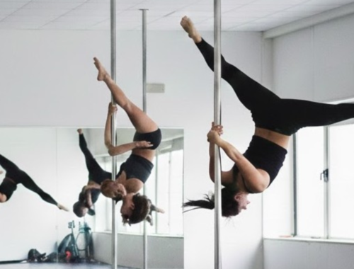 Cours de pole dance avec plusieurs femmes suspendues à la barre, jambes levées