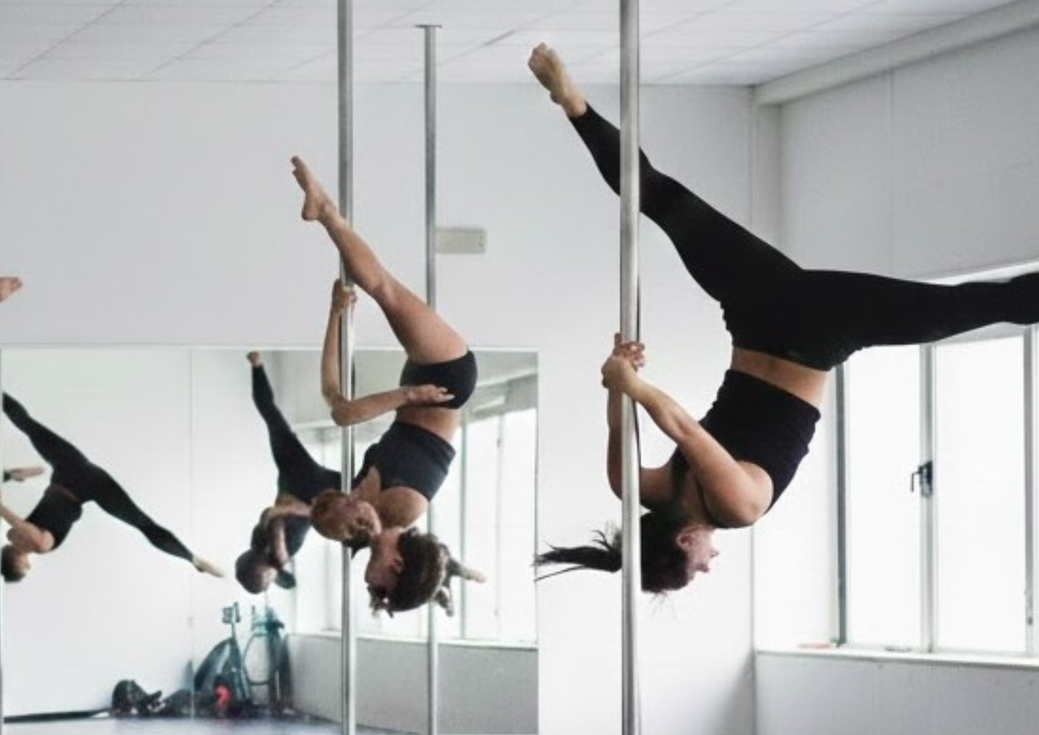 Cours de pole dance avec plusieurs femmes suspendues à la barre, jambes levées