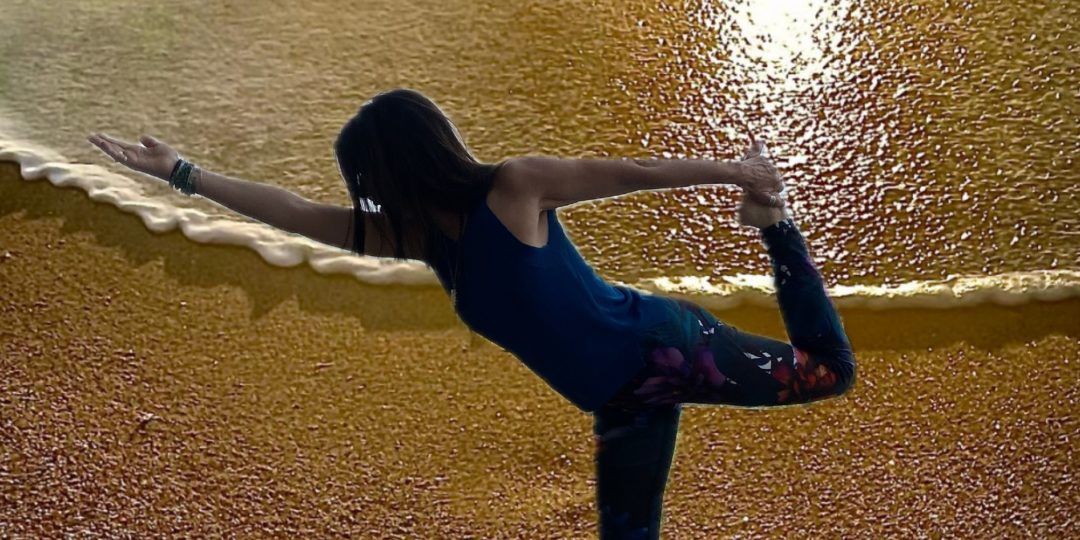 Femme réalisant une posture de yoga sur une plage au coucher du soleil