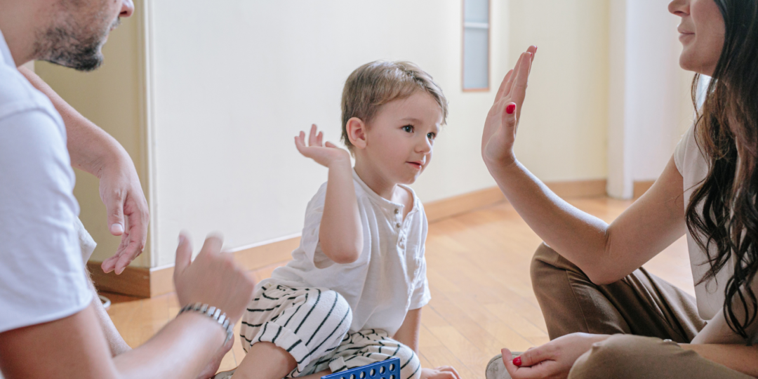 Enfant qui joue avec ses deux parents lors d'un atelier parent et bambin