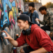 Un groupe de jeunes réalise des graffitis dans la rue à l'aide de bombes de peinture