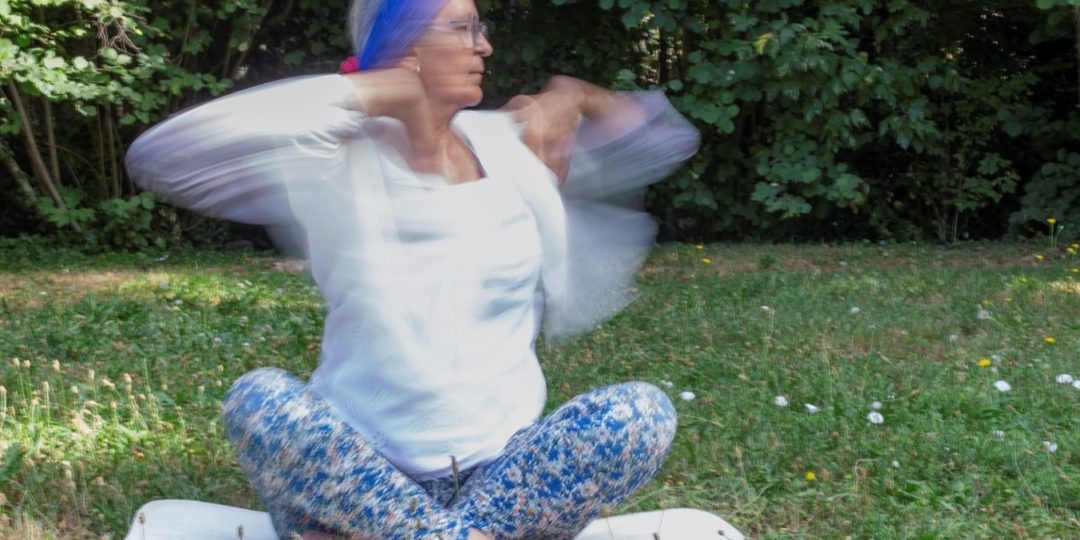 Pratiquante de Yoga Kundalini réalisant un exercice de respiration et de mouvements des bras en plein air pour favoriser l'énergie et le bien-être.