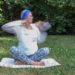 Pratiquante de Yoga Kundalini réalisant un exercice de respiration et de mouvements des bras en plein air pour favoriser l'énergie et le bien-être.