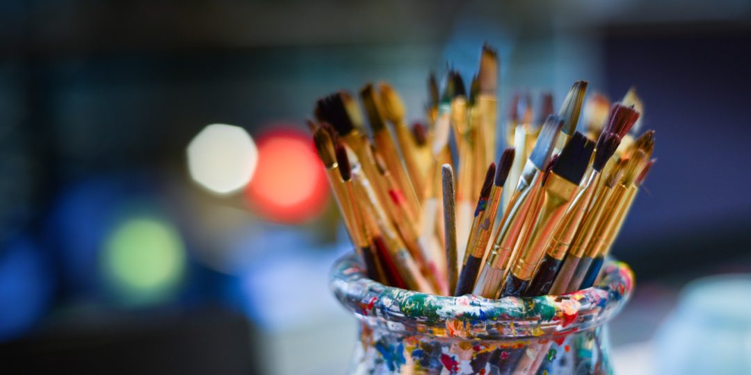 Pinceaux de peinture dans un pot coloré, prêts pour un atelier d'aquarelle ou une activité artistique créative.
