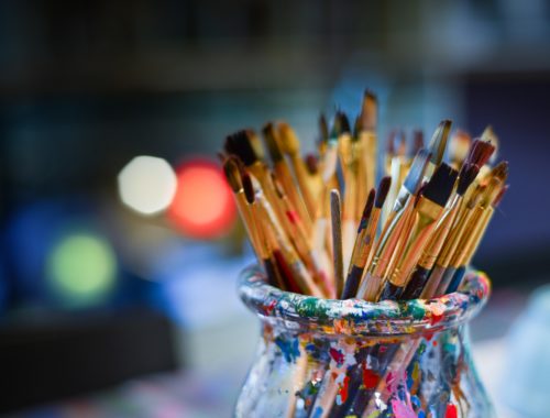 Pinceaux de peinture dans un pot coloré, prêts pour un atelier d'aquarelle ou une activité artistique créative.