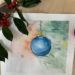 Aquarelle représentant une boule de Noël bleue suspendue à une branche de sapin, réalisée lors d'un atelier de peinture à l'aquarelle.