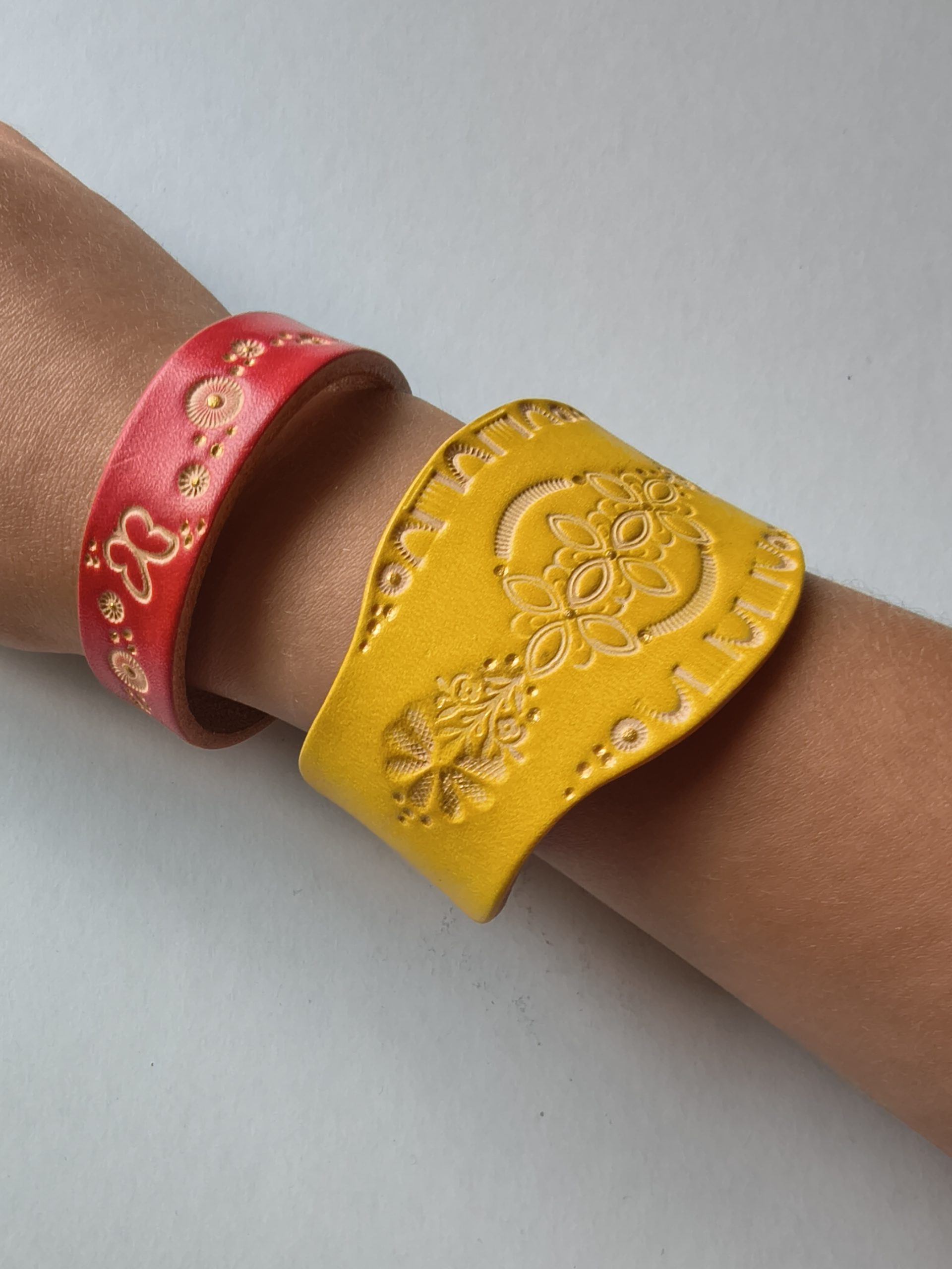 Bracelets en cuir artisanaux décorés de motifs embossés, réalisés lors d'un atelier créatif de maroquinerie.