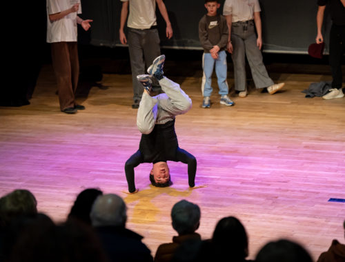 Spectacle où un jeune garçon effectue une figure de hip hop sur la tête.