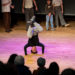 Spectacle où un jeune garçon effectue une figure de hip hop sur la tête.