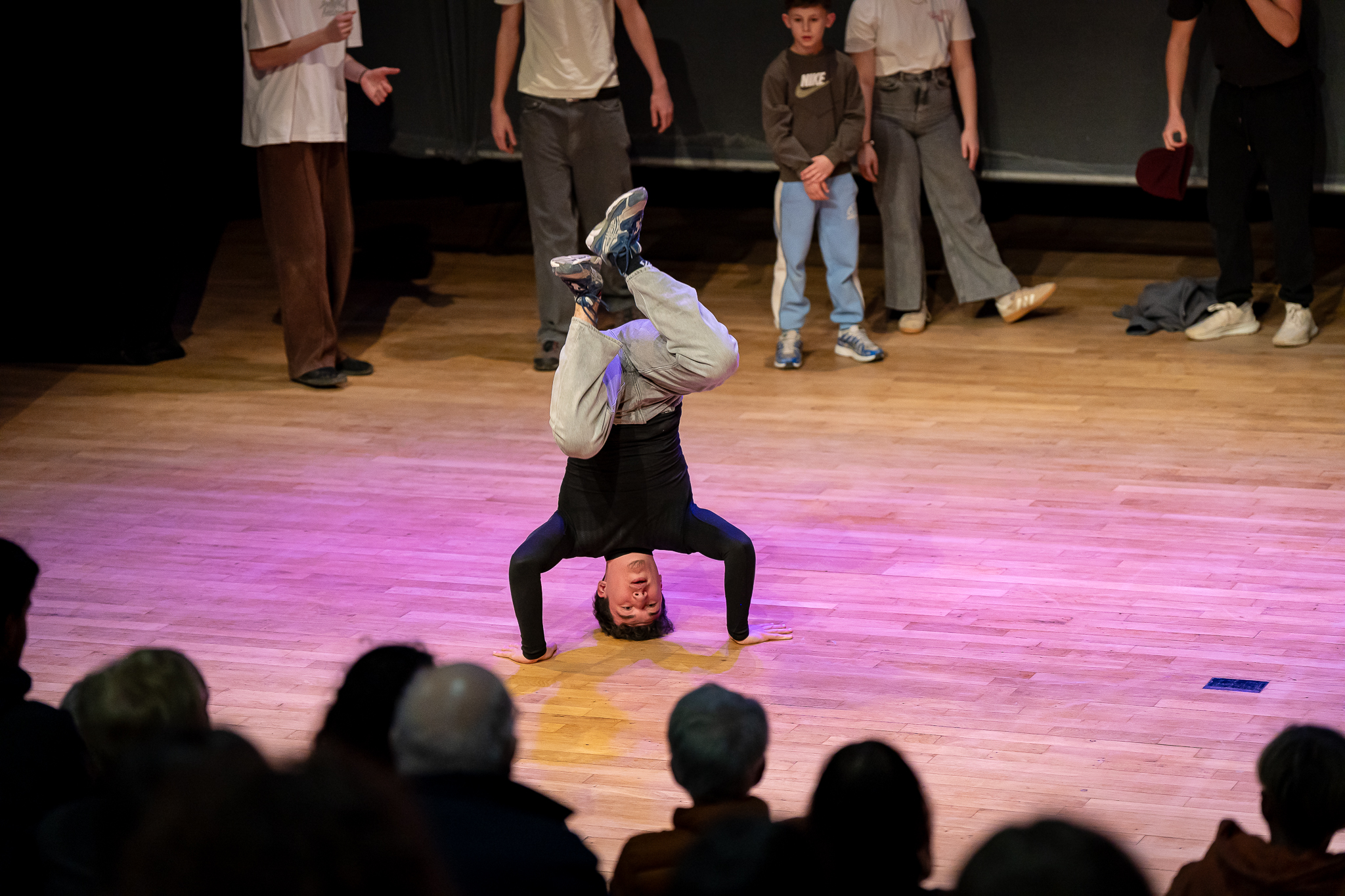 Spectacle où un jeune garçon effectue une figure de hip hop sur la tête.