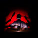 Scène de spectacle avec un personnage éclairé sous une lampe, dans une ambiance rouge et noire évoquant une quête de paix intérieure.