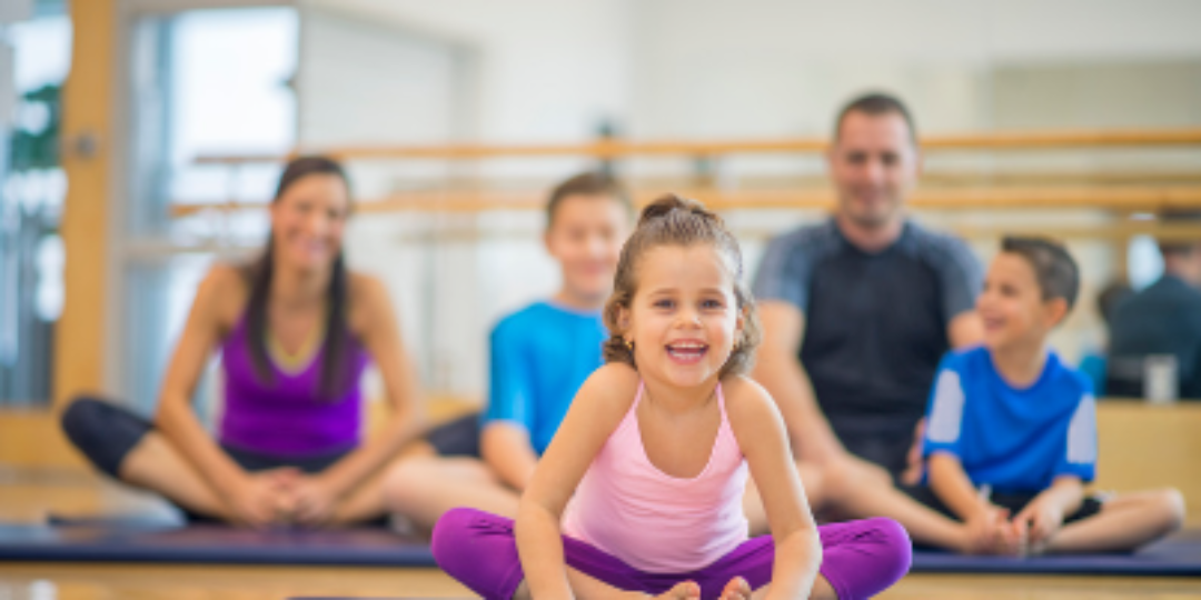 Atelier parent & bambin montrant au premier plan un enfant en tailleur accompagné de sa famille au loin.