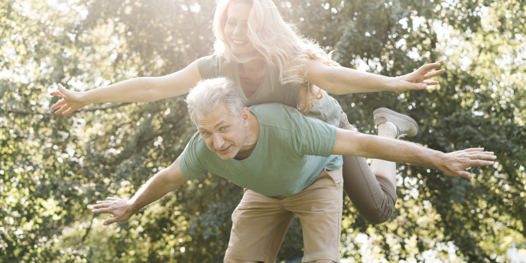 Couple de seniors s'amusant dans un parc, illustrant une conférence sur le vieillissement actif, la santé et le bien-être des seniors.