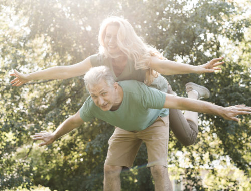 Couple de seniors s'amusant dans un parc, illustrant une conférence sur le vieillissement actif, la santé et le bien-être des seniors.