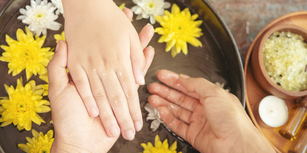 Soin des mains en institut avec bain floral, fleurs flottantes et rituel de bien-être pour hydrater et détendre la peau.