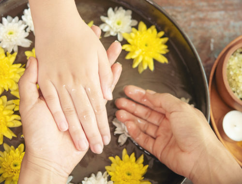 Soin des mains en institut avec bain floral, fleurs flottantes et rituel de bien-être pour hydrater et détendre la peau.