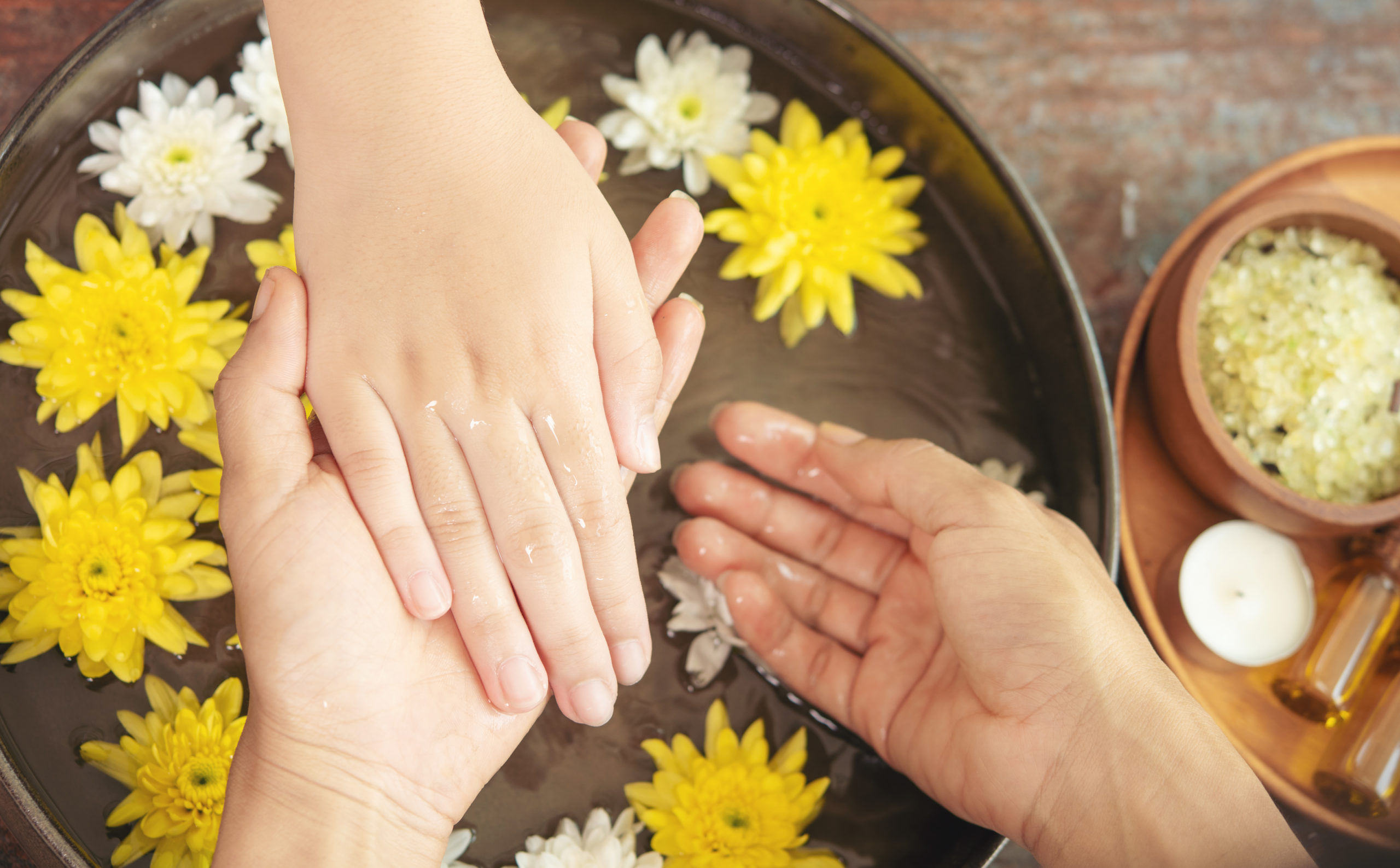 Soin des mains en institut avec bain floral, fleurs flottantes et rituel de bien-être pour hydrater et détendre la peau.