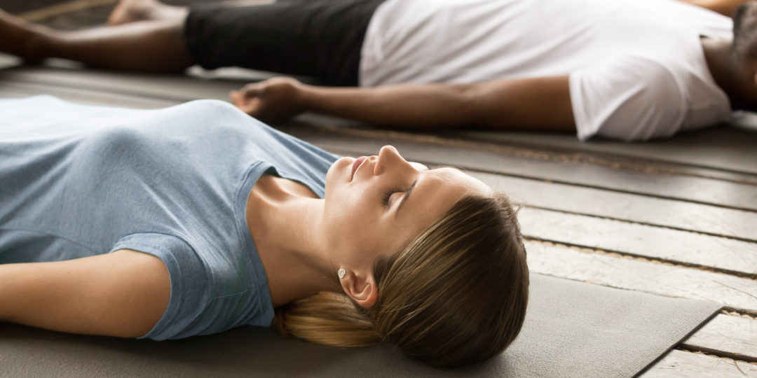 Participants allongés sur des tapis de sol durant une séance de sophrologie consacrée à la relaxation profonde et au bien-être pendant la saison hivernale.