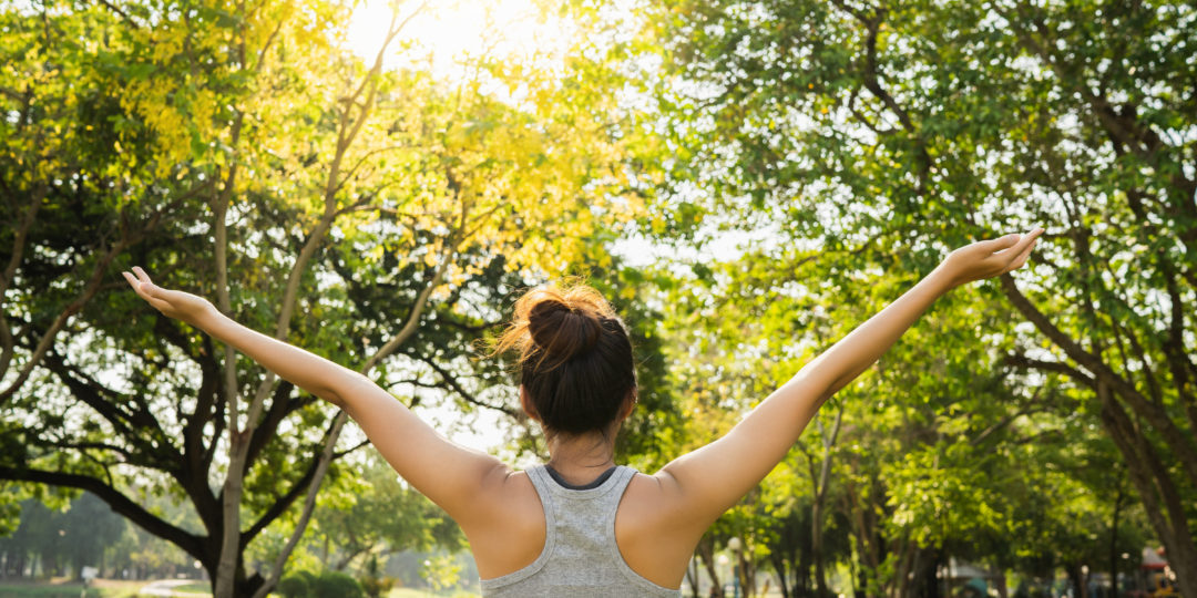 Personne s'étirant en pleine nature pour prendre soin de soi, favoriser le bien-être physique et mental et profiter d'un moment de détente.