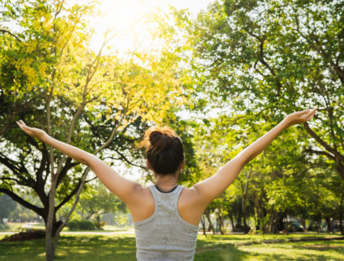 Personne s'étirant en pleine nature pour prendre soin de soi, favoriser le bien-être physique et mental et profiter d'un moment de détente.