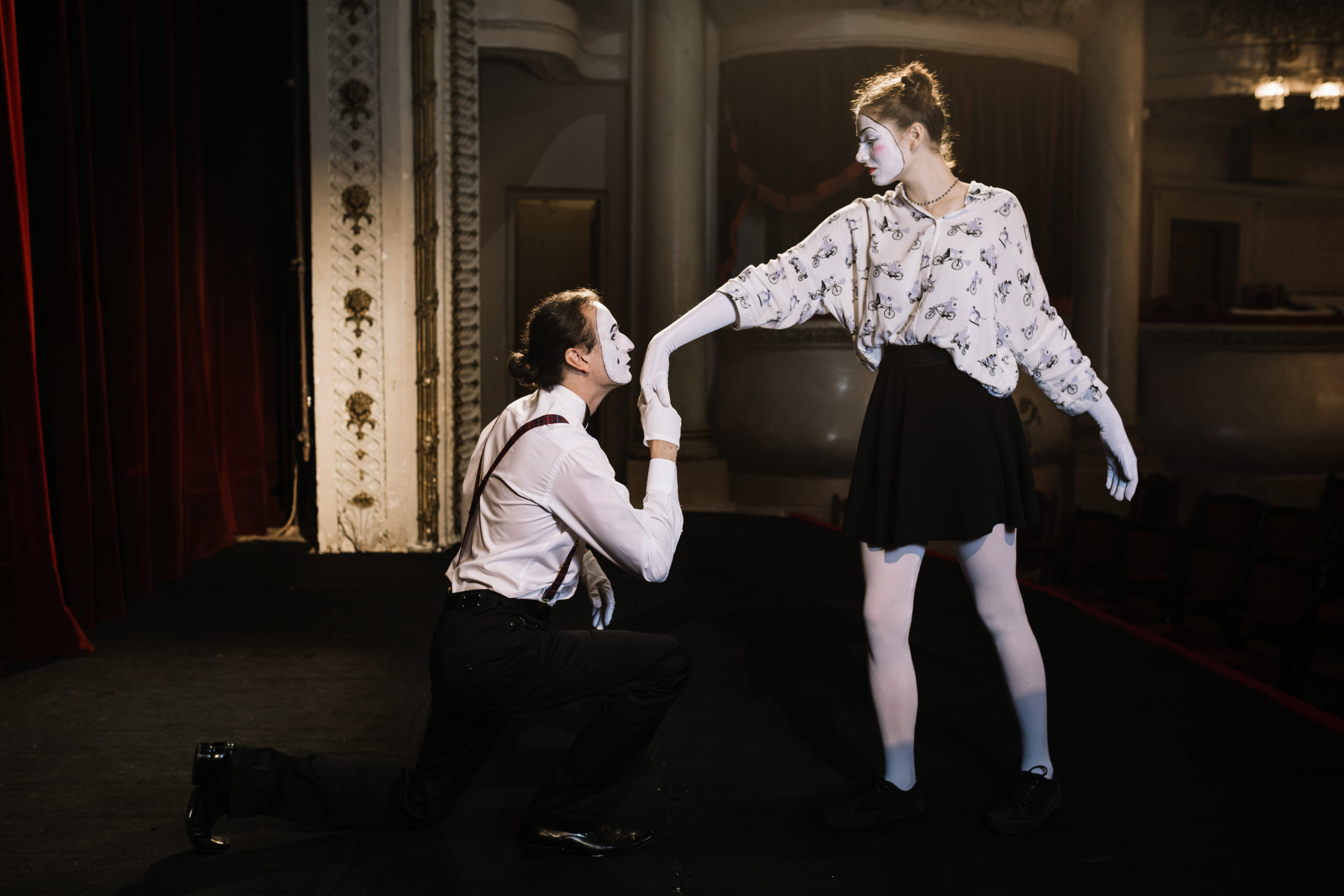 Deux artistes maquillés en mime interprètent une scène de théâtre burlesque sur une scène, illustrant un atelier d'expression corporelle et de jeu théâtral.