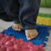 Jeune enfant marchant pieds nus sur un parcours sensoriel lors d'un atelier parent-bambin dédié au développement de la motricité.