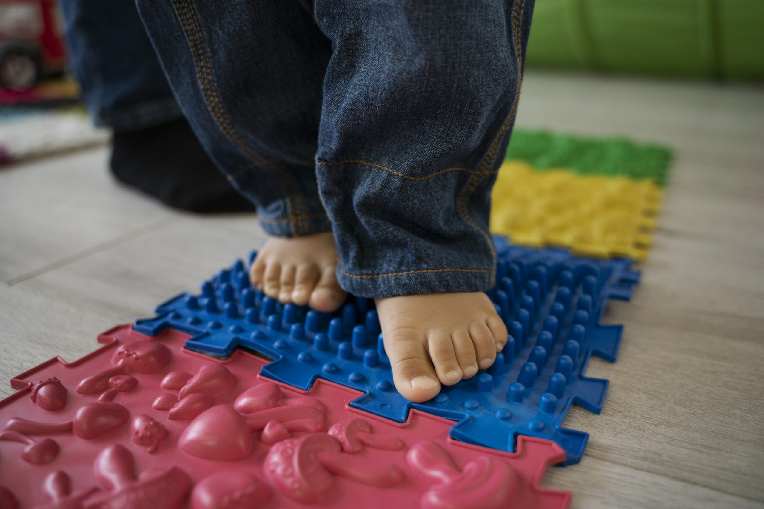 Jeune enfant marchant pieds nus sur un parcours sensoriel lors d'un atelier parent-bambin dédié au développement de la motricité.
