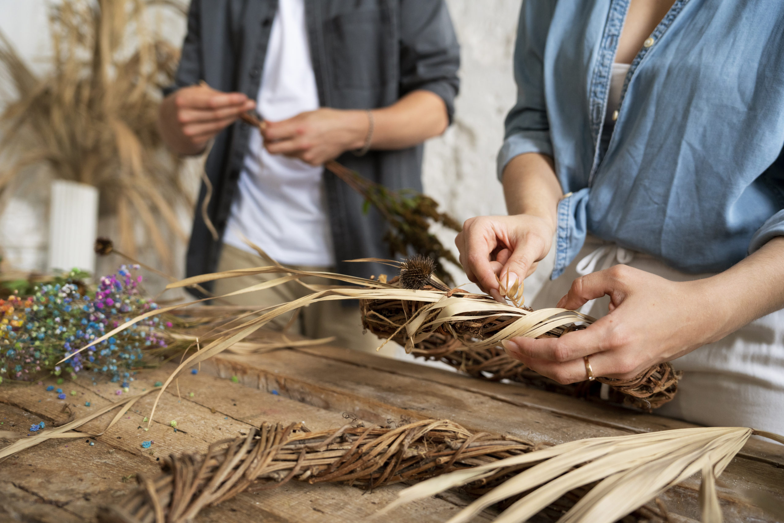 Participants réalisant un atelier de vannerie en tressant des fibres végétales pour créer un objet artisanal à la main.