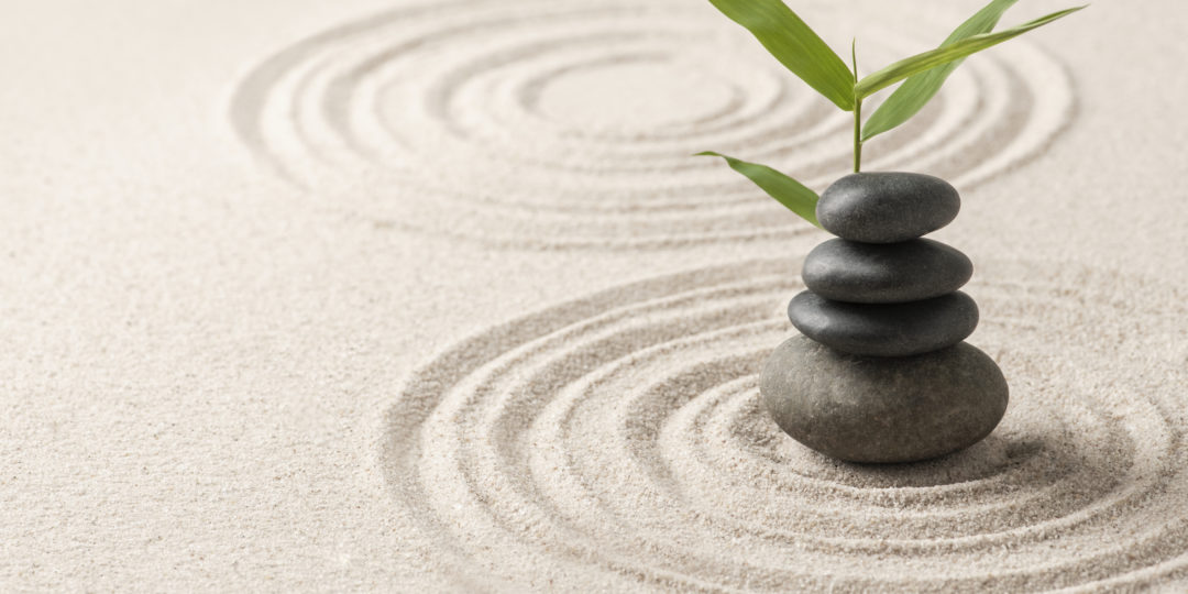 Galets empilés sur un jardin de sable zen avec une branche de bambou, symbolisant l'équilibre, le calme et un atelier de bien-être consacré à l'hiver, saison du Grand Yin.