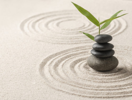 Galets empilés sur un jardin de sable zen avec une branche de bambou, symbolisant l'équilibre, le calme et un atelier de bien-être consacré à l'hiver, saison du Grand Yin.