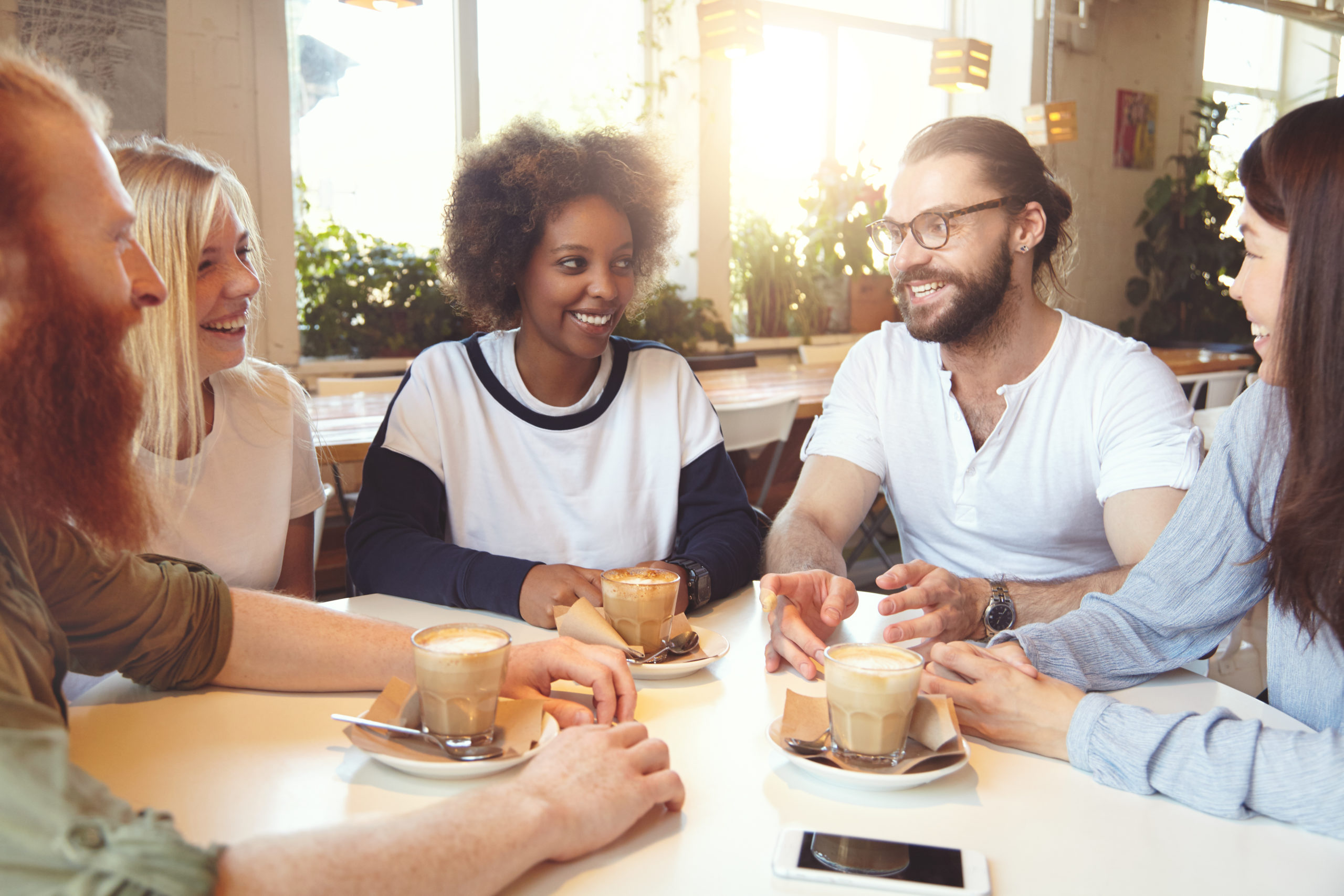 Groupe de personnes échangeant autour d'un café dans un espace convivial, favorisant le bien-être, le partage et les échanges.