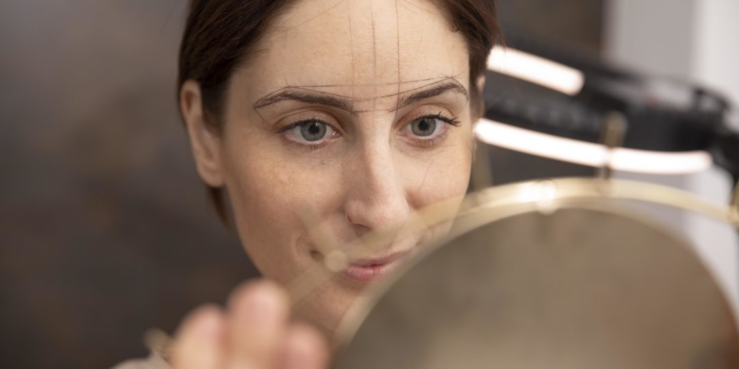 Conseillère en visagisme analysant les traits du visage d'une participante devant un miroir pour un conseil personnalisé.