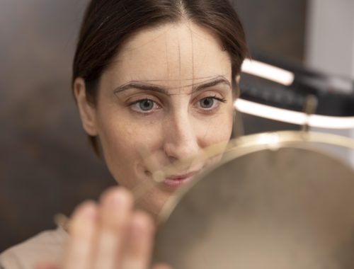 Conseillère en visagisme analysant les traits du visage d'une participante devant un miroir pour un conseil personnalisé.