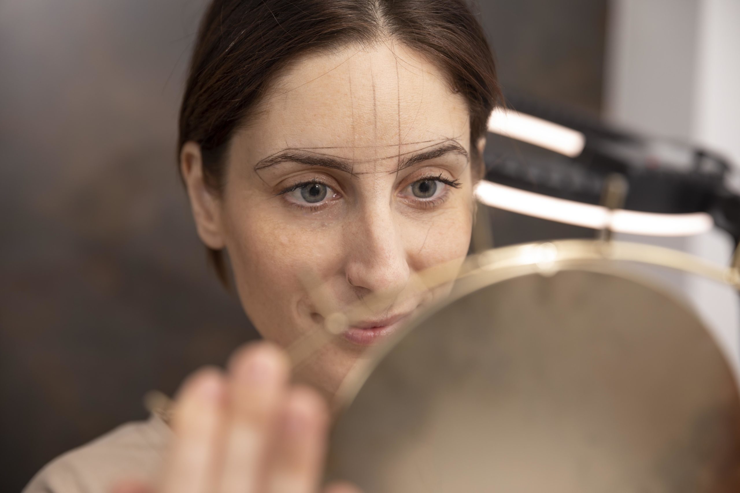 Conseillère en visagisme analysant les traits du visage d'une participante devant un miroir pour un conseil personnalisé.