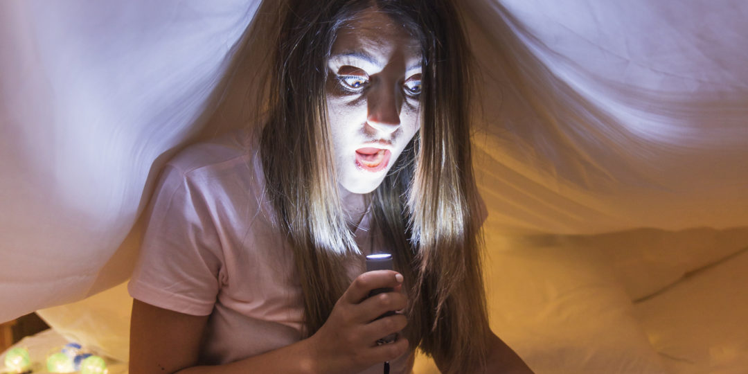 Personne lisant un livre à la lumière d'une lampe dans une ambiance chaleureuse, idéale pour un atelier de lecture ou un moment de conte.